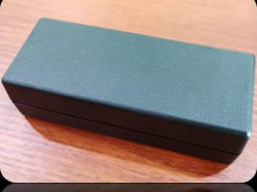 Dark grey desktop adapter enclosure with a fine matte texture